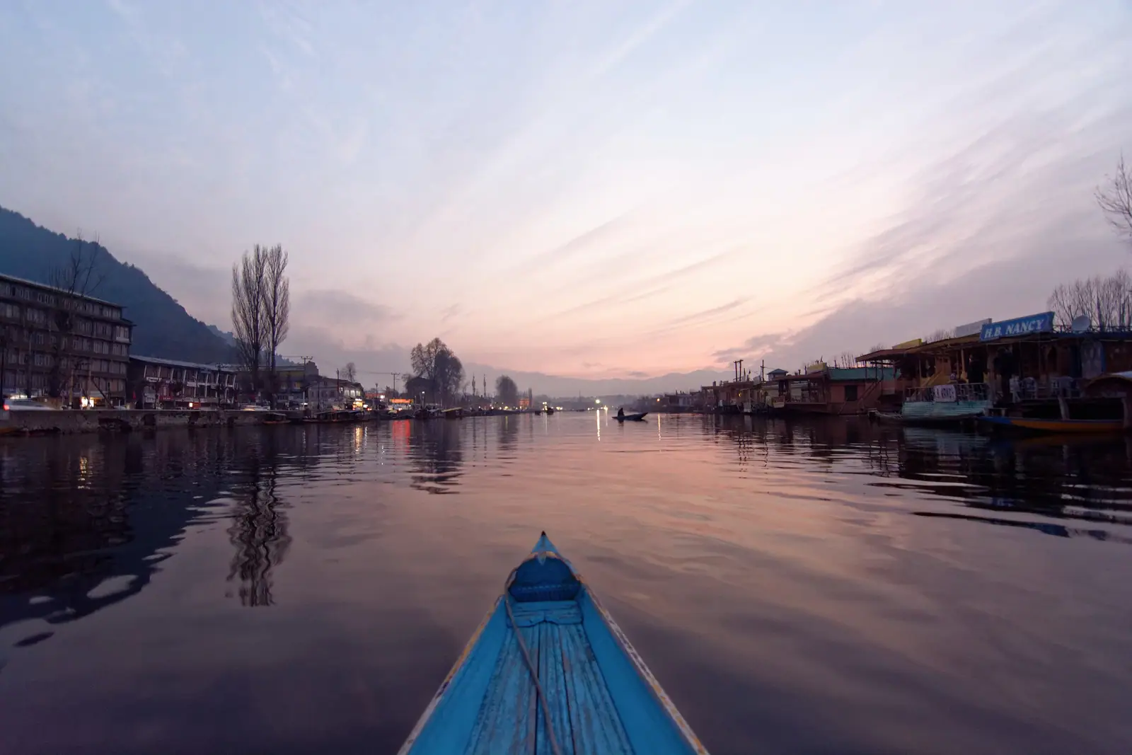 A shikara glides across Dal Lake at dusk in Srinagar